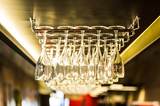 Wine glasses hanging upside down on a rack in warm golden light