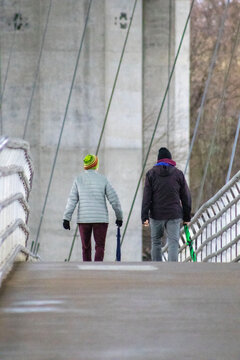 Two people walking across a pedestrian bridge in winter clothes