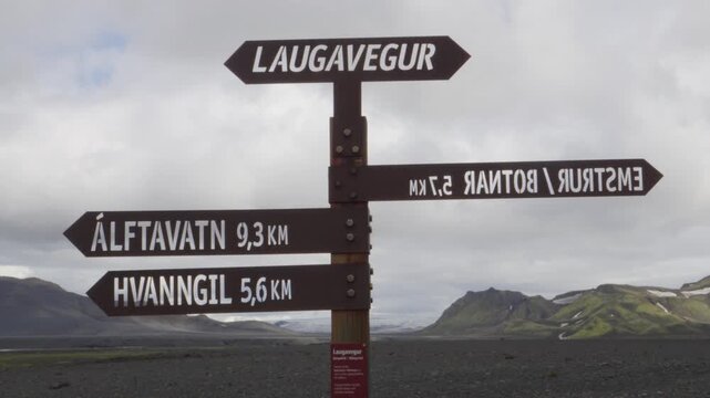 Journey on Iceland's Laugavegur trail, an iconic hiking path through dramatic volcanic landscapes. A signpost guides adventurers to destinations like &Aacute;lftavatn and Hvannagil amidst remote mountains.