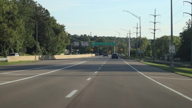 Shaky video from a point of view of driving down a three lane road with another car merging into the lane.