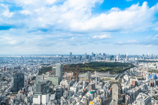 Panoramic aerial view of yoyogi park and shinjuku skyscraper, skyline from shibuya in tokyo japan under bright blue sky, sun and white cloud
