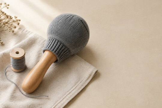 Grey wool sock on darning mushroom with thread, mending craft and sustainable repair concept