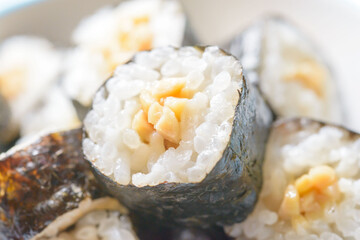 Close-up cross-section of natto maki sushi roll showing white rice and golden fermented soybeans © kei u
