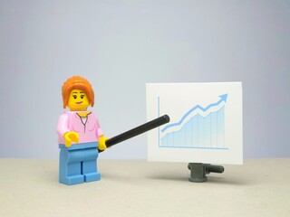Fototapeta premium Indonesia - November 29, 2023 : Mini toy figure of businesswoman at table with blurred background. Miniature photography concept design. Minifigure of teacher or mentor character at class room.