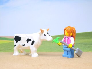 Obraz premium Indonesia - December 1, 2023 : Mini toy figure of people at table with blurred background. Miniature photography concept design. Farmer give green leaves plant.