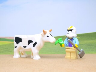 Obraz premium Indonesia - December 1, 2023 : Mini toy figure of people at table with blurred background. Miniature photography concept design. Farmer give green leaves plant.