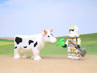 Obraz premium Indonesia - December 1, 2023 : Mini toy figure of people at table with blurred background. Miniature photography concept design. Farmer give green leaves plant.
