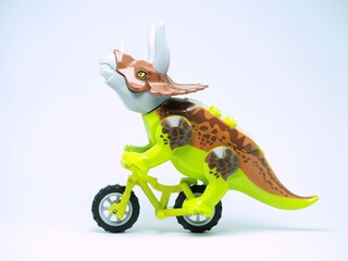 Fototapeta premium Indonesia - October 3, 2023 : Mini toy of action figure at table with blurred background. Miniature photography concept. Riding the bicycle conceptual design.