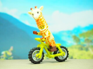 Fototapeta premium Indonesia - October 3, 2023 : Mini toy of action figure at table with blurred background. Toy photography concept. Riding the bicycle conceptual design.