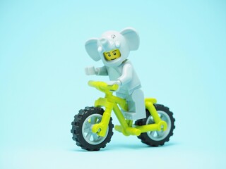Fototapeta premium Indonesia - October 3, 2023 : Mini toy of action figure at table with blurred background. Toy photography concept. Riding the bicycle conceptual design.