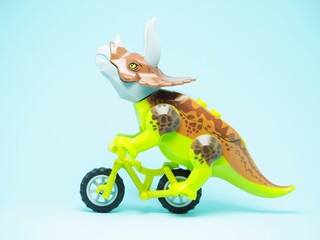 Fototapeta premium Indonesia - October 3, 2023 : Mini toy of action figure at table with blurred background. Miniature photography concept. Riding the bicycle conceptual design.