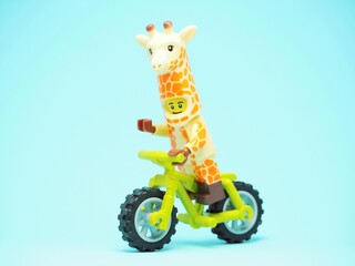 Fototapeta premium Indonesia - October 3, 2023 : Mini toy of action figure at table with blurred background. Toy photography concept. Riding the bicycle conceptual design.
