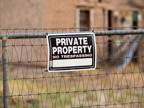 Fence holds a bold No Tresspassing, Private Property" warning sign