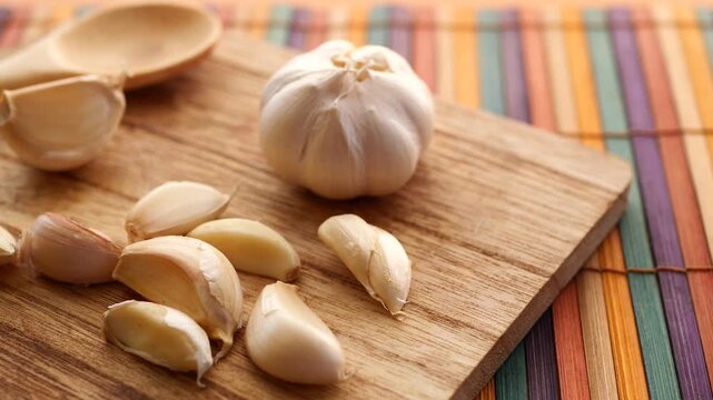 Close up of fresh garlic cloves on wooden cutting board with dynamic sliding movement in kitchen setting