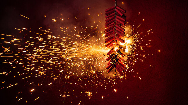 Red firecracker with golden sparks exploding brightly in dark background creating festive celebration effect