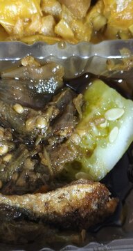 Close-up view of delicious home-cooked meal featuring fried fish, eggplant, and vegetables, showcasing a healthy and satisfying culinary experience