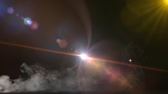 Optical lens flare with vibrant colorful light rays and bokeh spots shines across low smoke on black.