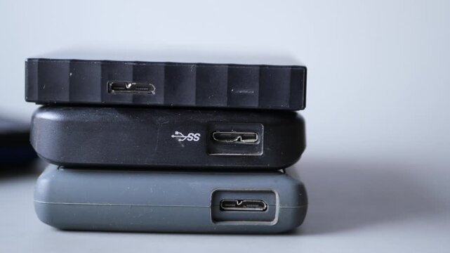 Macro view of external hard drives stacked showing various usb connection ports on white background