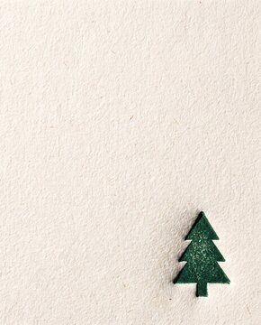 Debossed fir tree on textured cream cotton paper with empty space above