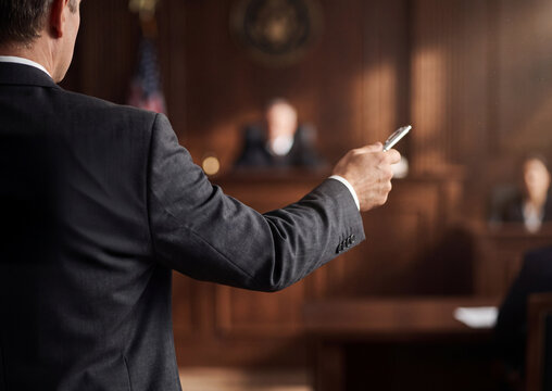 Lawyer standing in a wood paneled courtroom presenting a case before the presiding judge