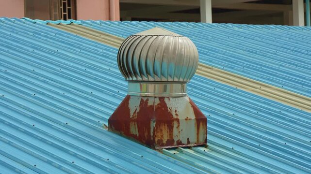 Rusty metal roof turbine ventilator on a blue corrugated roof
