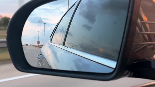 Side View Mirror Reflection of Highway and Sunset Sky While Driving