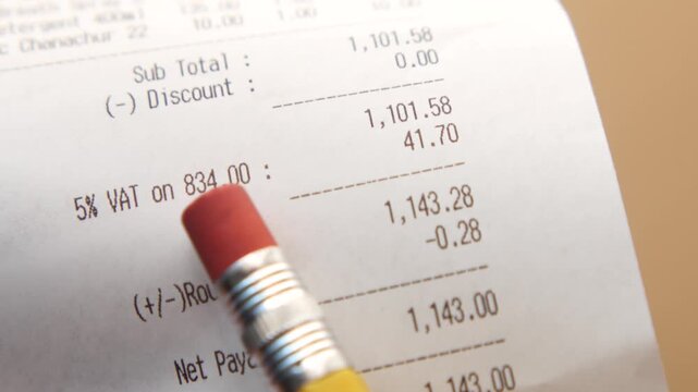 A close up view of a paper receipt with various numbers and calculations, shot with a slow motion camera movement