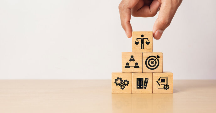 Hand holding wooden block with Ethical icons, business ethics and corporate compliance concept