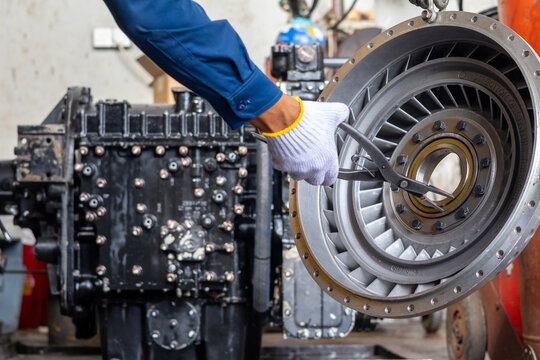 Technician installs retaining circlip on torque converter stator using pliers in mechanical workshop.