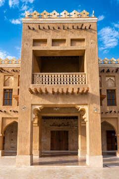 Traditional mud-plastered tower building with wooden beams, carved arches, and decorative parapet at historic souq in Al Khor Qatar.