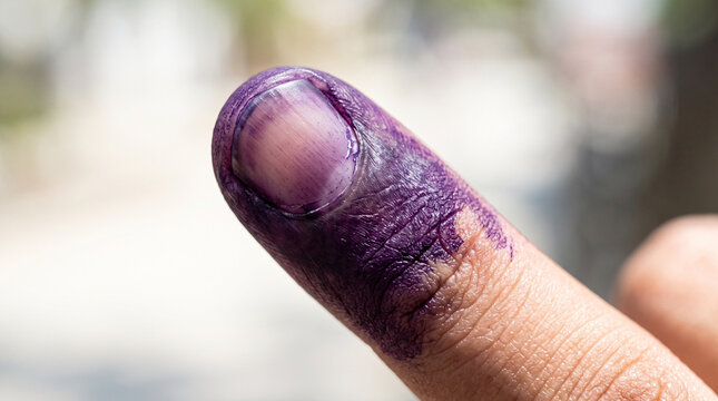 Extreme close-up of a single finger marked with purple ink at the tip