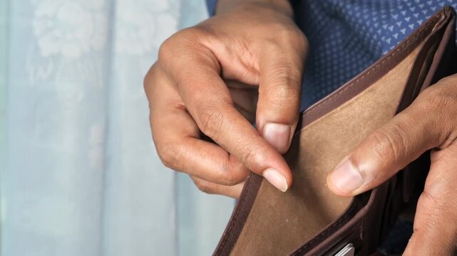 A person checking an empty wallet, indicating financial hardship and economic struggle, close-up shot of hands and wallet