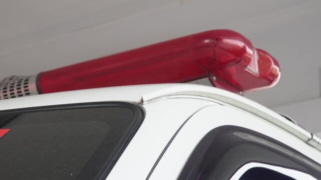 Close up view of a red emergency siren lightbar and speaker mounted on the white roof of an ambulance or police vehicle, emergency response equipment, public safety concept, and warning signal device.