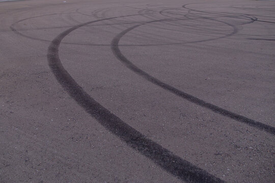 Tire skid marks on asphalt pavement showing curved braking tracks