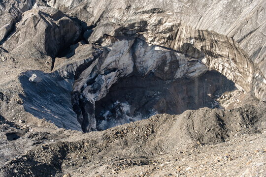 Dark ice cave cavity in Lenin Glacier with melting ice forming waterfalls, Pamir mountains