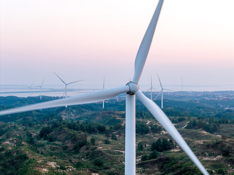 rows of wind turbines on the green rolling hills at dusk
