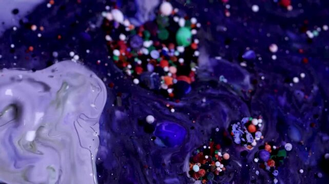 Video macro sinematik menampilkan cairan abstrak berwarna ungu, biru, putih, dan hitam yang bergerak perlahan seperti galaksi cair. Pola marmer berputar dan mengalir secara organik