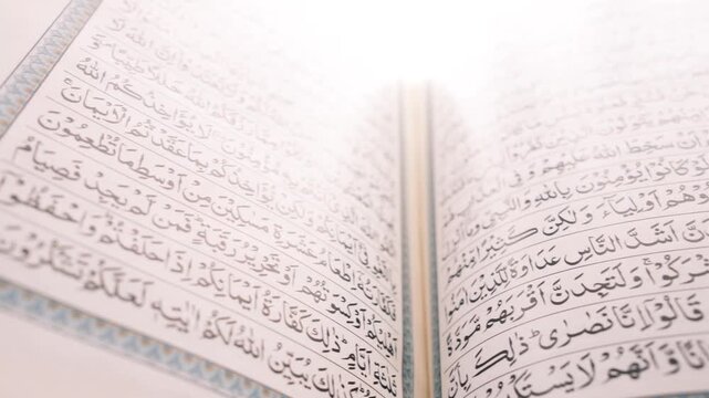 Macro view of open holy quran book with white bright background lighting in cinematic slow motion footage