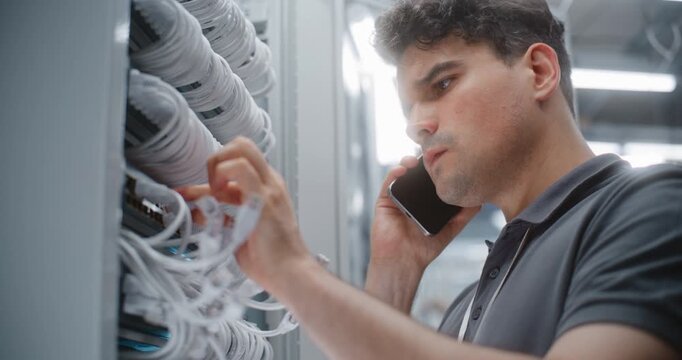 Male IT Technician Reviews Physical Network Connections During Smartphone Call, Confirming Port Identification and Rack Cabling as Part of Coordinated Data Center Infrastructure Audit Process.