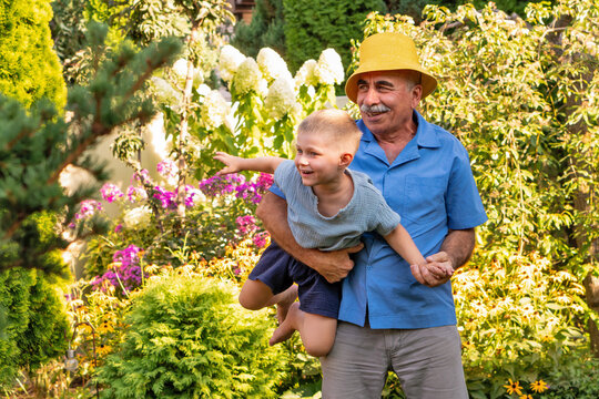 Grandfather Playing Airplane With Grandson in Sunny Garden