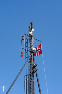 Norwegian flag flying on a ship's mast with navigation equipment against clear blue sky