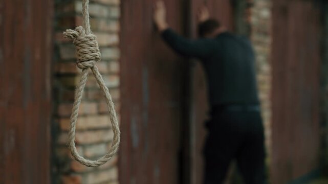 A nervous man on the background of a rope with a noose for suicide. Nervous breakdown. A man on the verge of death. Suicide by hanging. Human psychology.