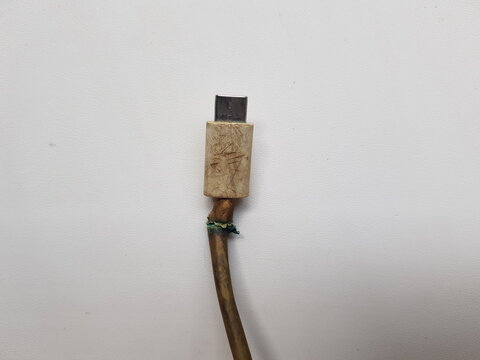 Broken USB Type C connector cable with frayed wire and burn mark isolated on white background