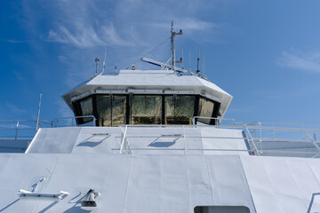 Modern white ferry boat bridge with navigation equipment under a clear blue sky © heerim studio