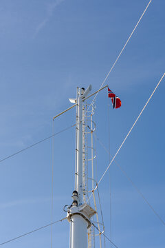 White ship mast with a national flag against a bright blue sky background