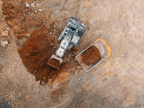 Excavator filling haul truck with excavated soil from pit Aerial top view