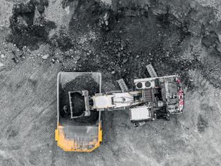 Aerial view of excavator loading dump truck with iron ore in open pit mine for industrial banner © Parilov