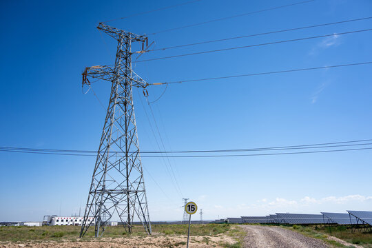 power transmission tower and solar panels under blue sky
