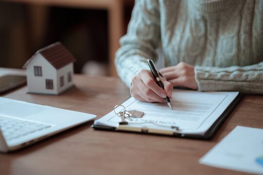 A real estate professional reviews and signs a property agreement, representing a home purchase, mortgage approval, investment, and legal transaction.