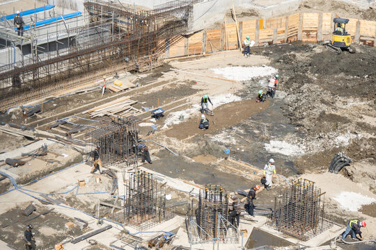 大型建築物の基礎工事現場で位置と寸法を測定する作業員